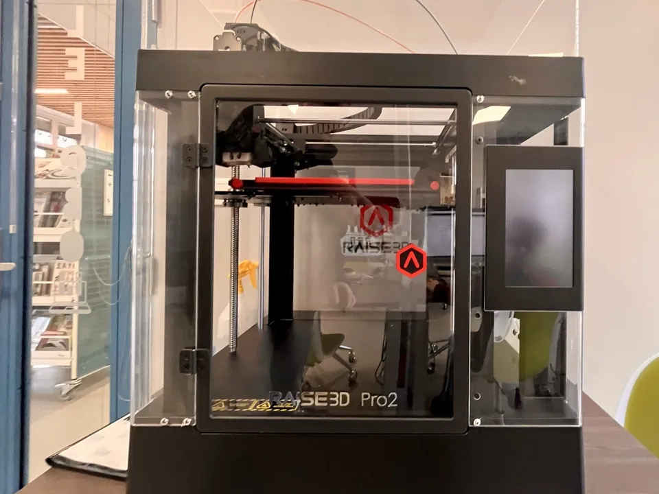 A Raise3D Pro2 enclosed 3D printer with clear doors and side panels, on display in a public library.