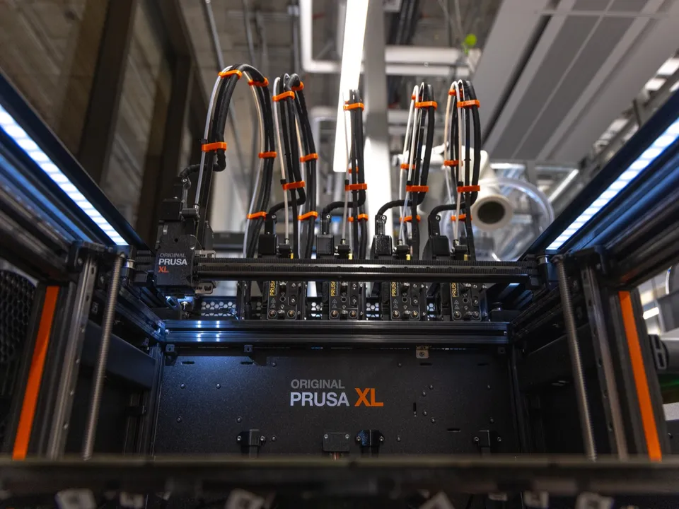 Looking into an Original Prusa XL enclosure, with the cable bundles of its docked toolheads lined up along the back of the frame.